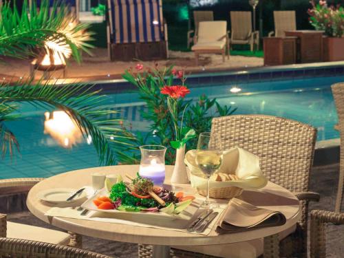 a table with a plate of food next to a pool at Mercure Hotel Frankfurt Eschborn Ost in Eschborn