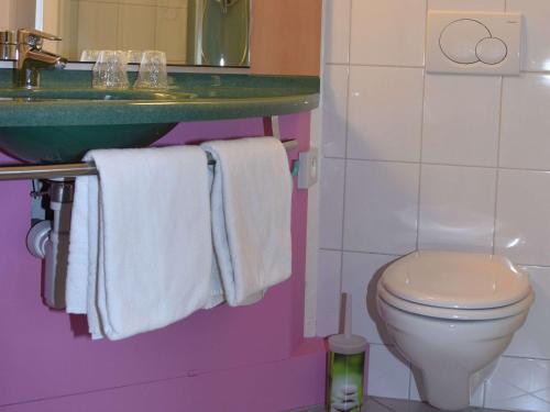a bathroom with a toilet and a sink and towels at Mercure Paris Le Bourget Aeroport in Le Blanc-Mesnil