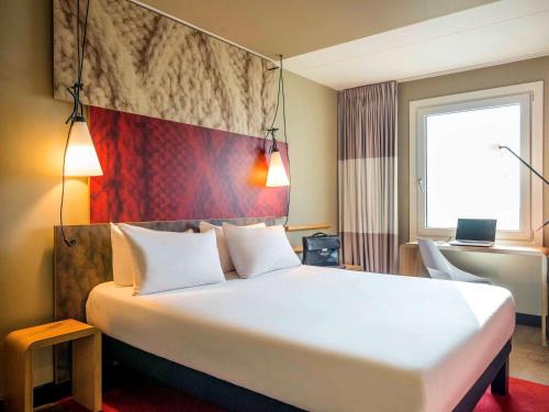 a hotel room with a large bed and a large window at Ibis Schiphol Amsterdam Airport in Badhoevedorp