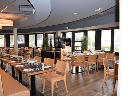 a restaurant with wooden tables and chairs and windows at ibis Tours Nord in Tours