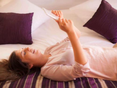 a woman laying on a bed holding a book at Mercure Strasbourg Centre in Strasbourg