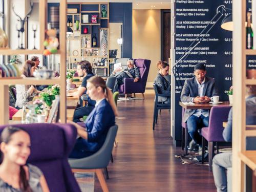 a group of people sitting in chairs in a restaurant at Mercure München City Center in Munich