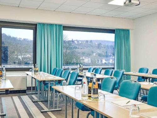 a dining room with tables and chairs and a large window at Mercure Hotel Koblenz in Koblenz