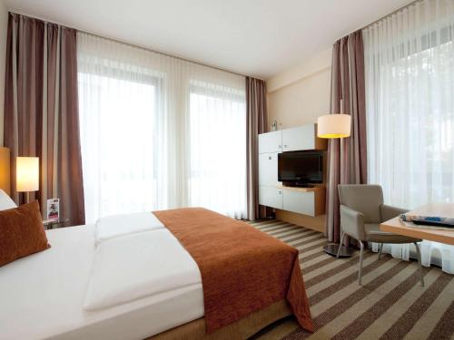 a hotel room with a large bed and a desk at Mercure Hotel Aachen Am Dom in Aachen
