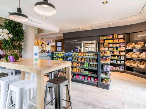 a grocery store with a counter and stools at Novotel Suites Paris Issy Les Moulineaux in Issy-les-Moulineaux