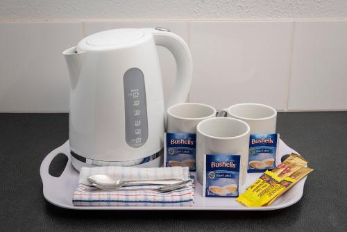 a tray with a coffee maker and some milk at The Beach Motel Hervey Bay in Hervey Bay