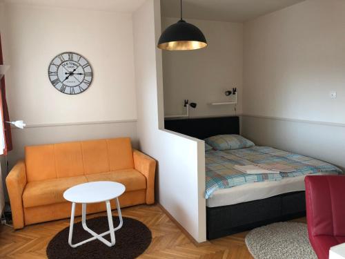 a bedroom with a bed and a chair and a clock at RT Home Vendégház in Szombathely