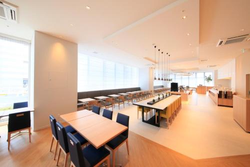 a dining room with tables and chairs and windows at Richmond Hotel Himeji in Himeji
