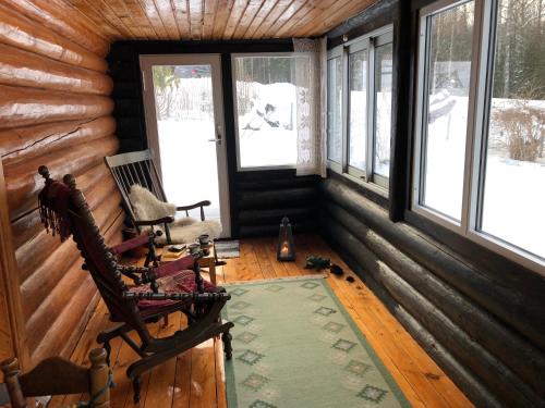 an empty room with a rocking chair in a log cabin at Rabens Cottage in Bengtsfors