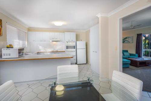 a kitchen with white cabinets and a table and chairs at The Beach Motel Hervey Bay in Hervey Bay