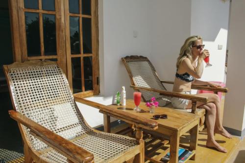 a woman in a bikini sitting at a table with two chairs at Garden Beach Hotel in Arugam Bay