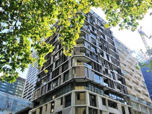 a tall apartment building with trees in front of it at Orange Stay Sydney CBD in Sydney