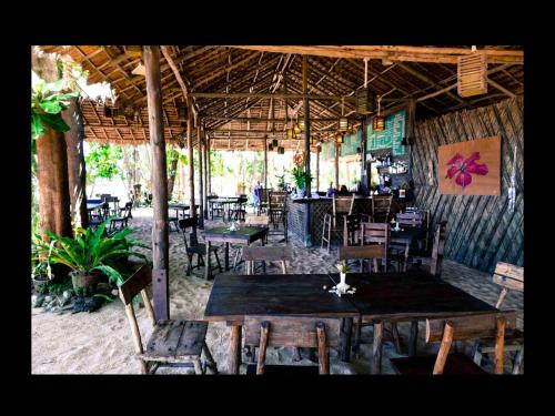 a restaurant with wooden tables and chairs and a tables and chairs at Hapla beach cottage in Ko Kho Khao