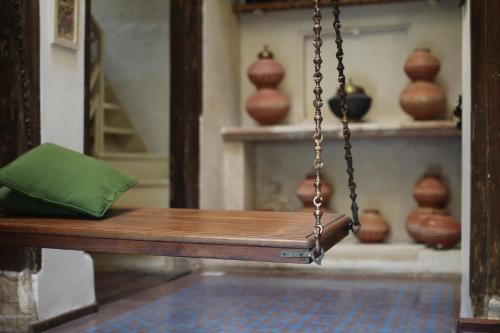 a wooden swing with a green pillow sitting on it at French Haveli in Ahmedabad