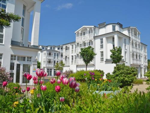 een tuin voor een wit gebouw met bloemen bij Seepark Sellin - Apt. 382 in Ostseebad Sellin