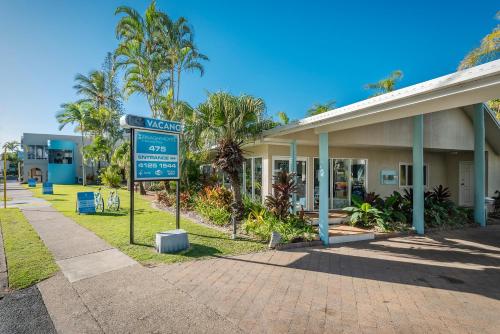 a large white building with palm trees in front of it at The Beach Motel Hervey Bay in Hervey Bay