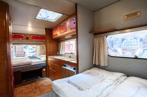 a small room with a bed and two windows at Treck Hostel in Ghent