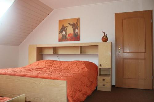 a bedroom with a bed with an orange comforter at Ferienwohnung Storchennest in Lohsa