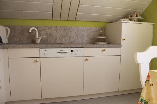 uma cozinha com armários brancos e um lavatório em Ferienwohnung Storchennest em Lohsa