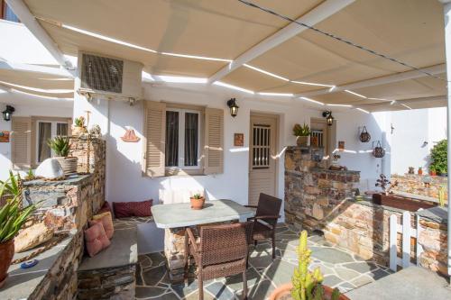 a patio with a table and chairs and a stone wall at Irini pension in Platis Yialos Sifnos