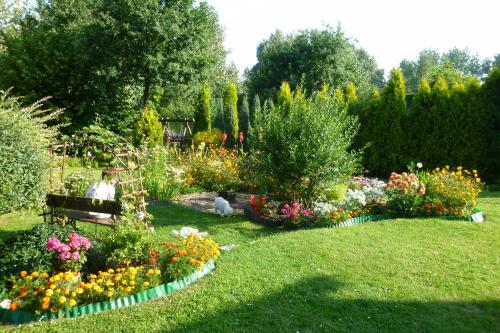 a garden with flowers and a bench in the grass at Folwark Anna in Kamienica Polska