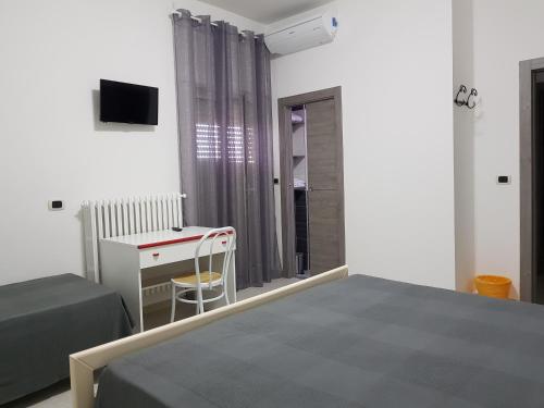a bedroom with a bed and a desk and a window at Holiday B&B in Vico del Gargano