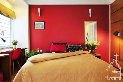 Chez Tram Homestay في هانوي: غرفة نوم بحائط احمر مع سرير ومكتب