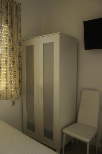 a bedroom with a white cabinet and a chair at Mar de Rosas in O Grove