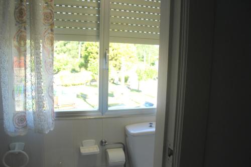 a bathroom with a window and a white toilet at Mar de Rosas in O Grove
