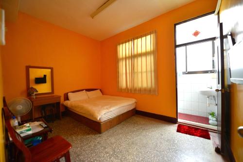 1 dormitorio con paredes de color naranja, 1 cama y ventana en 鹽舍休閒民宿 en Beimen