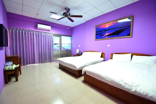 Beimenにある鹽舍休閒民宿の紫色のベッドルーム(ベッド2台、天井ファン付)