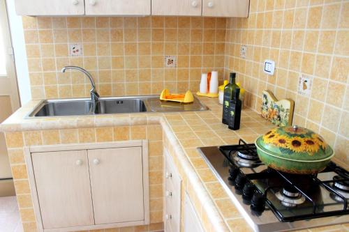 a kitchen with a sink and a stove with a pot on it at Home Holiday Salento Monica's House Pescoluse in Marina di Pescoluse