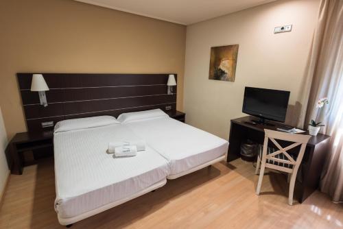 a bedroom with a large white bed and a television at Las Ventas in Utebo