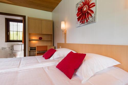 a bedroom with a large white bed with red pillows at Hostellerie d'Inzepré in Barvaux