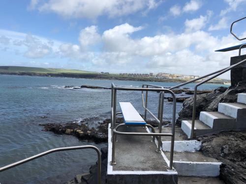 a bench sitting on the steps near the water at Kilkee Holiday Homes Type A by Trident Holiday Homes in Kilkee