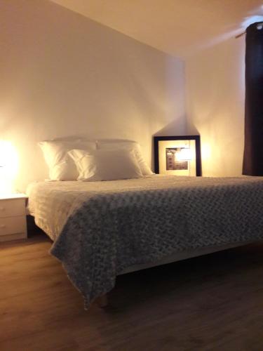 1 dormitorio con 1 cama con sábanas blancas y espejo en La Lune ô Collines - Gîte, en Lédenon