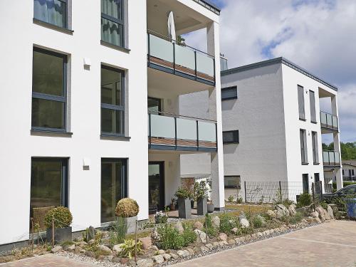 un bâtiment blanc avec des plantes devant lui dans l'établissement Haus "Jasmund" in Sellin - WG01 im EG mit Kamin und Terrasse, à Sellin