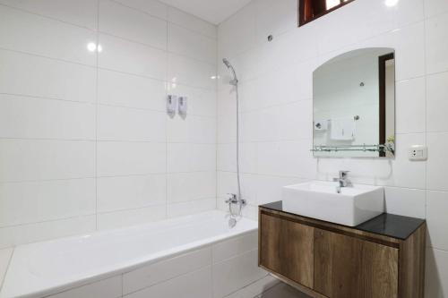 a white bathroom with a sink and a bath tub at Mk House Tendean in Jakarta