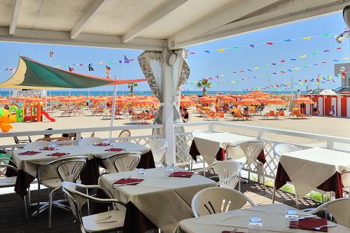 restauracja ze stołami i krzesłami oraz plaża w obiekcie Hotel & Residence Cavalluccio Marino w Rimini