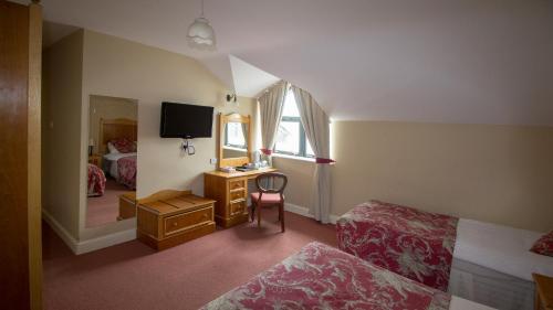 a bedroom with a bed and a desk and a tv at Óstán Oileán Acla in Achill Sound