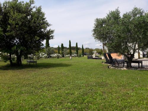 a park with benches and trees in the grass at La Lune ô Collines - Gîte in Lédenon