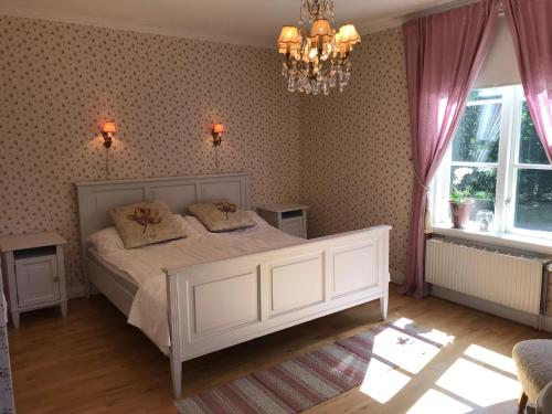 a bedroom with a white bed and a chandelier at Hotell Plevnagården in Malmköping