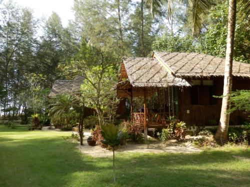 a small house with a straw roof in a yard at Hapla beach cottage in Ko Kho Khao