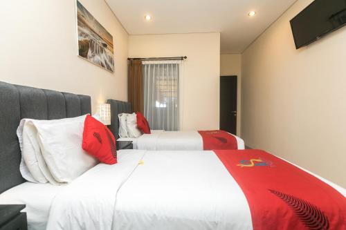 a hotel room with two beds with red pillows at Rantun's Place Nusa Dua in Nusa Dua