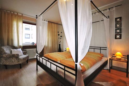 バート・ハルツブルクにあるDomizil Keniaのベッドルーム(天蓋付きベッド1台、椅子付)