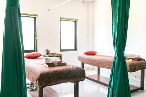 a room with two beds with green curtains at Rantun's Place Nusa Dua in Nusa Dua