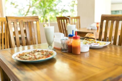 a wooden table with a plate of pizza and drinks at Rantun's Place Nusa Dua in Nusa Dua