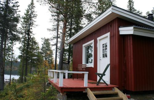 a red cabin with a porch and a table on a deck at Aurora Camp Kurravaara in Kurravaara