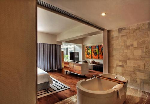 a bathroom with a bath tub and a bedroom at TS SUITES Seminyak Bali in Legian