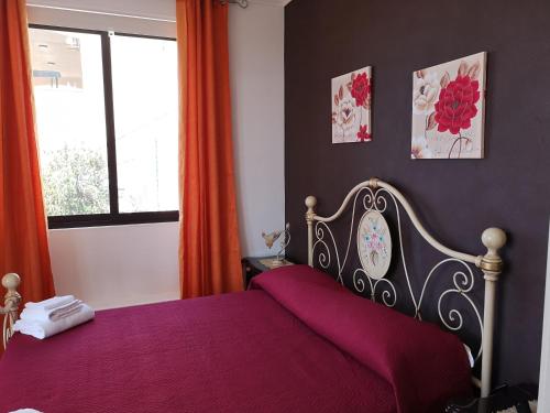 a bedroom with a bed with a purple blanket and a window at Villa Sabbiadoro in Noto Marina